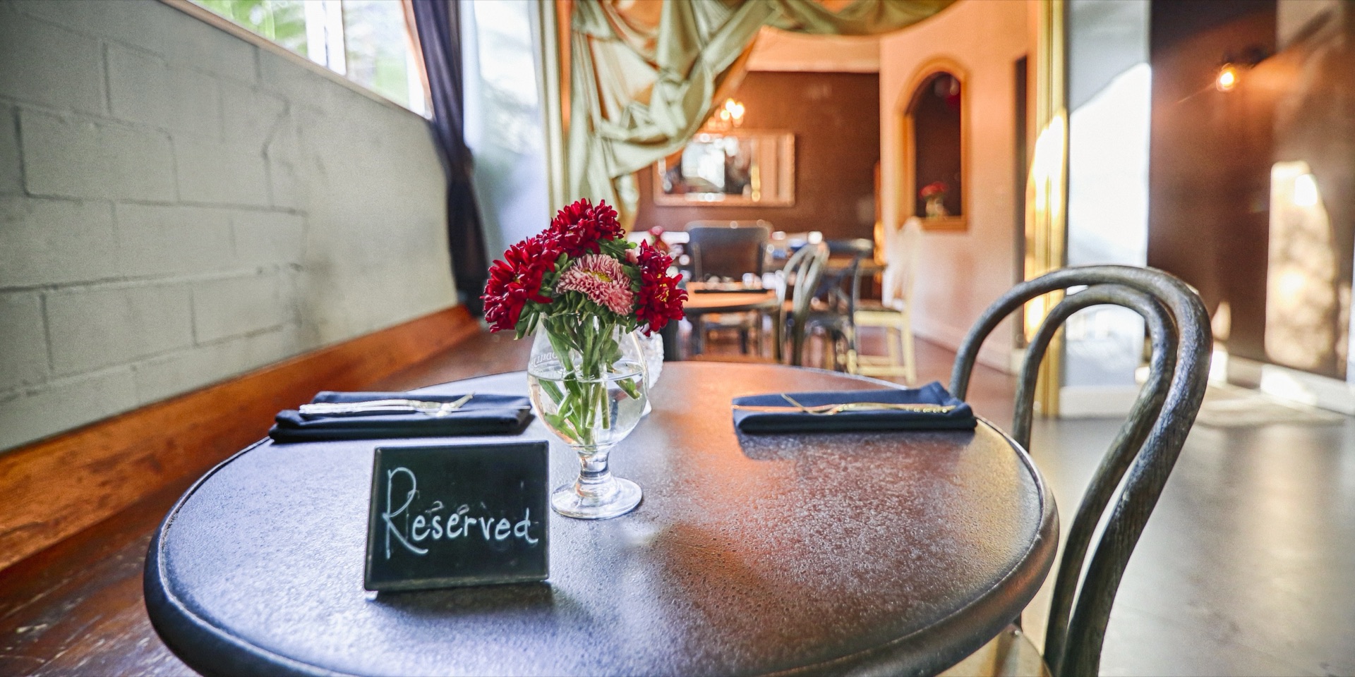 A reserved bistro table with red flowers at Hopfields